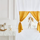 In einem weißen Raum steht das KraftKids Puppentheater Kasperletheater Leinen grau Pusteblumen inkl.. Teleskopstange steht hinter gelben Vorhängen, auf dem Tisch stehen ein Spielzeug-Schaukelpferd und ein Bauklotz, die die Fantasie der Kinder anregen.