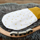 Ein KraftKids Strampelsack Herbst Winter Musselin gelbe Zitronen Babyschlafsack liegt auf einem grauen Kunstfellteppich, neben einer hölzernen Spielzeugeisenbahn und einer schwarz-weißen Spielzeugeisenbahn.