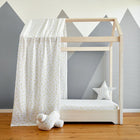 Ein modernes Hausbett mit Bettbaldachin Musselin gelbe Zitronen von KraftKids, farblich abgestimmte Bettwäsche und Stern- sowie Wolkenkissen. Dahinter eine Wand mit grauen Bergen-ideal fürs Musselin Kinderzimmer.