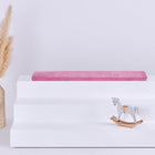 Eine dreistufige weiße IKEA TROFAST Sitzbank mit einem KraftKids GmbH Sitzauflage für Ikea TROFAST Cord Breitcord Rosa Kissen auf der obersten Stufe, einer Vase mit Pampasgras auf der linken Seite und einem kleinen weißen Schaukelpferd auf der unteren rechten Seite.