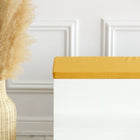 Eine hohe geflochtene Vase mit Pampasgras steht neben einer weißen Bank mit der KraftKids GmbH Sitzauflage für Ikea TROFAST Leinen in senfgelb, die an einer weiß getäfelten Wand steht.