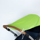 Ein KraftKids Sonnensegel weiße Punkte auf Grün ist am braunen Lenker eines marineblauen Kinderwagens befestigt und bietet stilvollen Sonnenschutz für Ihr Kind vor einem schlichten weißen Hintergrund.