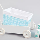 Ein weißer Spielzeugwagen mit dem KraftKids Körbchen weiße Pfeile auf Blau, einem handgenähten blauen Baumwollkorb mit weißen Pfeilen, steht neben pastellblauen und weißen Dekoblöcken auf hellgrauem Hintergrund. Ideal für die Aufbewahrung auf dem Wickeltisch.