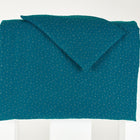 Das KraftKids Bettwäscheset Musselin in Petrol hat goldene Punkte auf 100% Baumwolle, ordentlich gefaltet und drapiert, um seine weiche Unterseite zu enthüllen - ideal für erholsamen Schlaf.