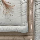 Draufsicht auf zwei KraftKids Wickelauflage Leinen leicht grünes Weiß gestapelt, mit getrocknetem Gras belegt und von sanftem Sonnenlicht beleuchtet - ideal für Ihren Wickelplatz.