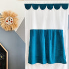 A KraftKids Puppentheater Kasperletheater aus Musselin mit goldenen Punkten auf Petrol inkl. Teleskopstange. Teleskopstange hängt an einer geometrisch-grauen Wand, daneben eine Löwen-Wanddeko aus Stroh und ein Teil einer Tafel mit bunten Kreidezeichnungen.