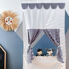 Ein verspieltes Kinderzimmer mit dem KraftKids Puppentheater Kasperletheater Musselin grau Punkte inkl. Teleskopstange. Teleskopstange mit zwei Puppen und grauen gepunkteten Vorhängen, einer fröhlichen Sonnenwanddekoration und einer Kreidetafel auf einer blau-weißen geometrischen Wand.