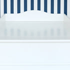 Ein KraftKids Wickelaufsatz weiß, passend für schmale 3er oder 4er Schubladen MALM Kommode und mit geschwungenen Kanten, steht vor einer Wand mit vertikalen blauen und weißen Streifen; die Oberfläche ist sauber und leer.